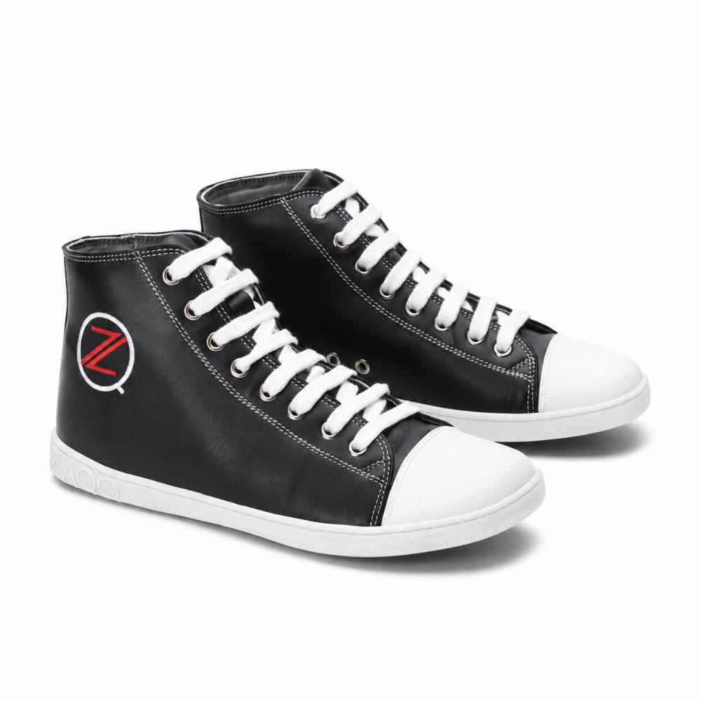 Et par klassiske svarte high-top sneakers fra ZAQQ CHUQQS har hvite lisser og tåkapsler, som hver viser en iøynefallende rød-hvit Z-logo. Sålene er laget av slitesterk gummisåle, noe som gir skoene et trendy, lett slitt utseende.