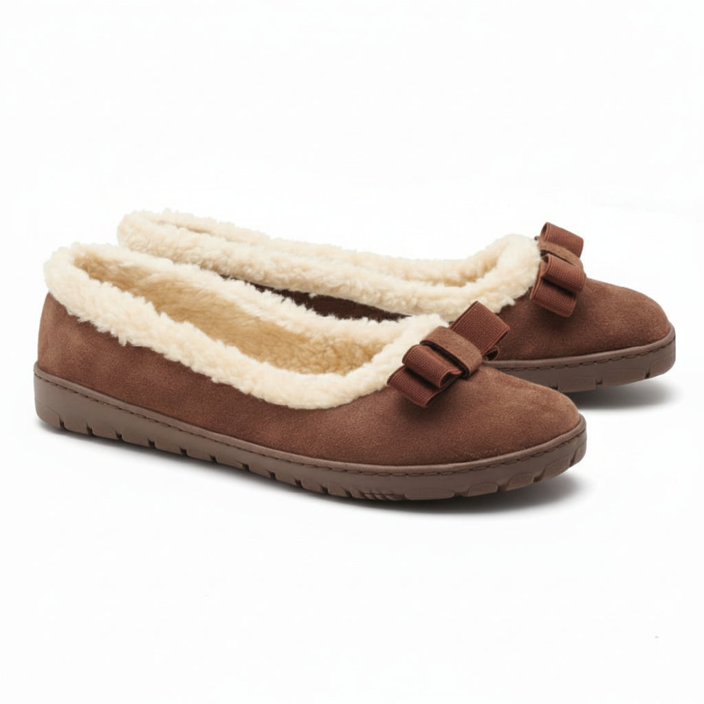 Der DAQIN Winter Brown von ZAQQ hat ein plüschiges, cremefarbenes Futter und dekorative Schleifen auf der Oberseite. Diese Slipper aus Veloursleder verfügen über eine flache, wildlederähnliche Textur und eine rutschhemmende Kautschuksohle für zuverlässigen Halt.
