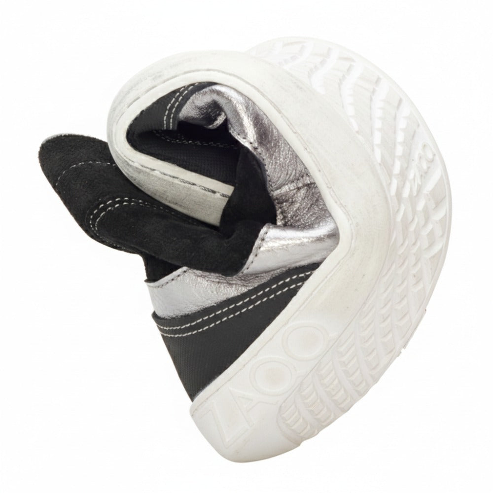 Ein weiß-schwarzer Midcut-Sneaker ist kunstvoll zu einem Herzen geformt und gibt den Blick auf die Sohle mit ihrem strukturierten Design und dem geprägten Wort „ZAQQ“ frei. Der Schuh FRANQY Black von ZAQQ ist mit metallischen und schwarzen Stoffakzenten verziert.