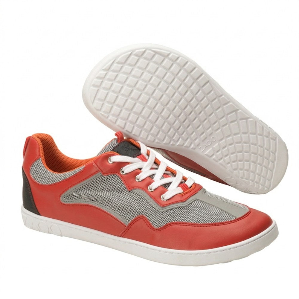 Die Sportschuhe QOPA Red von ZAQQ haben ein rotes und graues Obermaterial mit weißen Schnürsenkeln und weißen Sohlen. Ein Schuh steht aufrecht, während der andere angewinkelt ist, um das Profilmuster zu zeigen. Das Innenfutter ist orange und sorgt für Atmungsaktivität und ganztägigen Komfort.