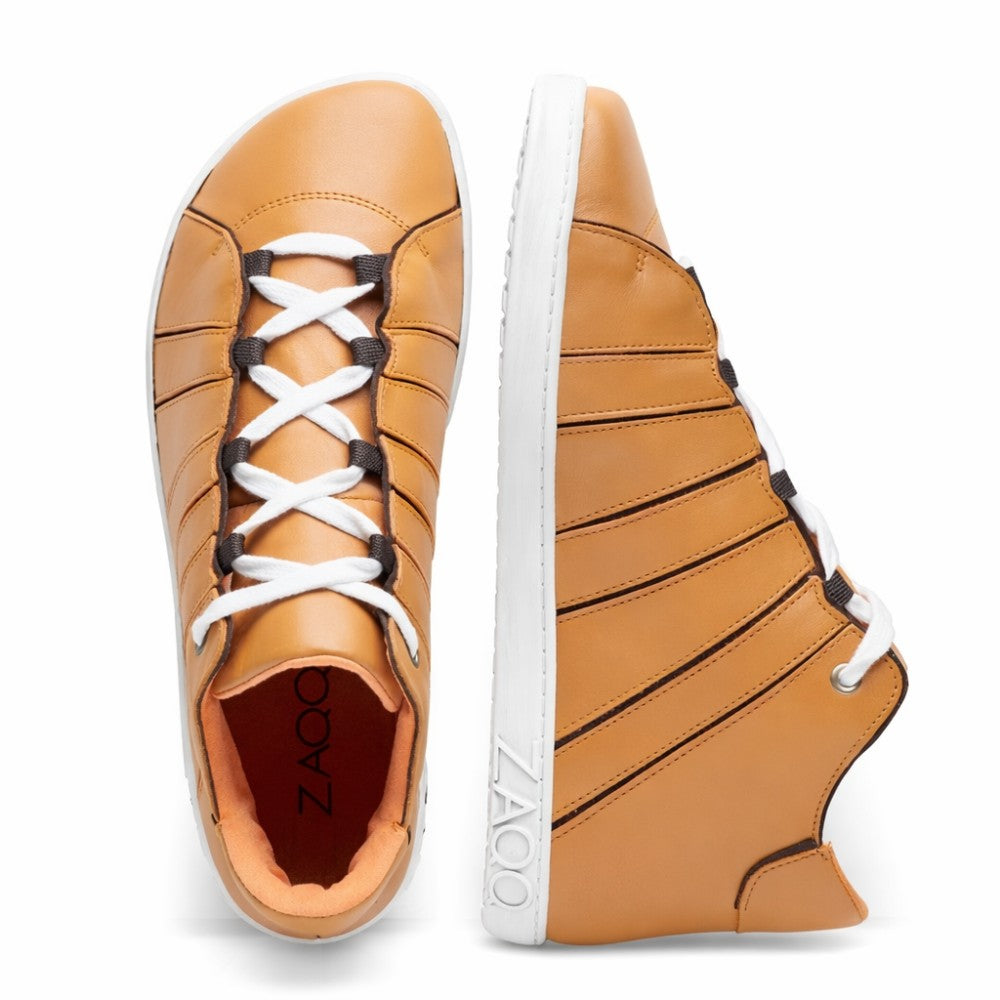 Wir präsentieren den QQQ Mid Sierra von ZAQQ: ein stilvolles Paar High-Top-Sneaker in Hellbraun, fachmännisch aus luxuriösem Nappaleder gefertigt. Diese Schuhe haben weiße Sohlen und Schnürsenkel mit auffälligen schwarzen Akzenten und zeigen stolz den Markennamen ZAQQ auf der Seite. Ein Schuh zeigt eine Draufsicht auf seine Schnürsenkel, während der andere sein von Barfußschuhen inspiriertes Streifendesign zeigt.