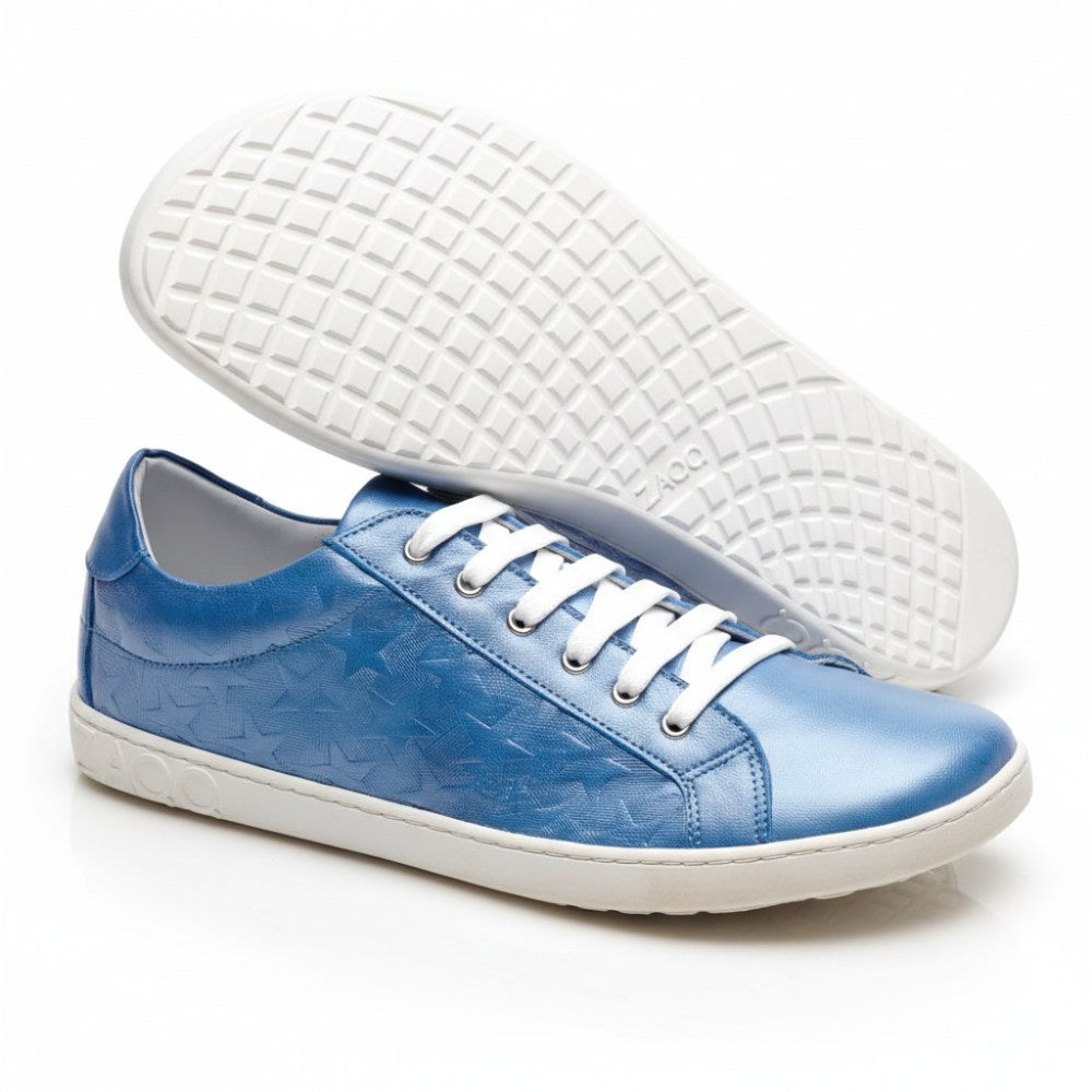 Der SLOQ Stars Blue von ZAQQ ist ein Paar glänzender blauer Sneaker mit Sternenmuster und weißer Sohle. Ein Sneaker steht aufrecht, während der andere auf der Seite liegt, wodurch das aufwendige Profilmuster der Sohlen hervorgehoben wird. Diese Schuhe sind aus glattem Nappaleder gefertigt und mit weißen Schnürsenkeln ausgestattet und vereinen nahtlos Stil und Komfort.