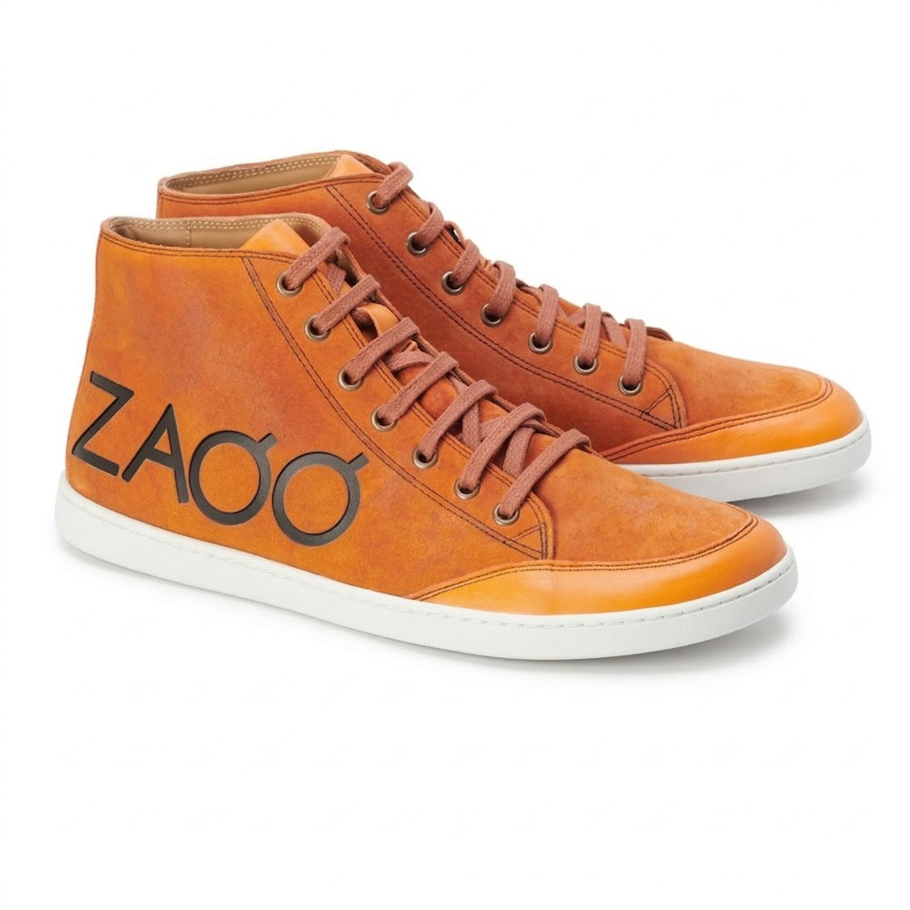 Die SQYLA Orange Sneaker von ZAQQ, perfekt für Damen, bestechen durch ihr leuchtend oranges Design mit braunen Schnürsenkeln und einer klassischen weißen Sohle. Die Seite ist mit dem Markennamen ZAQQ in fetten schwarzen Buchstaben verziert. Mit ihrem leicht abgenutzten Look verkörpern diese Sneaker eine Vintage-Ästhetik, die an Barfußschuh-Styles erinnert.
